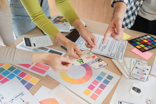 Diverse team reviewing design mockups during brainstorming session at office.