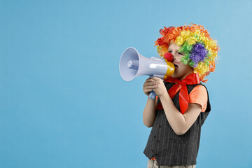 Little boy dressed like clown shouting in megaphone on light blue background, space for text....
