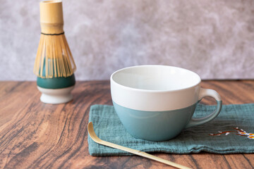 Empty matcha tea cup with chasen and bamboo whisk resting on wooden table