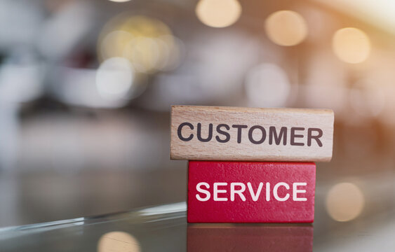 Customer service concept with wooden blocks stacked on a reflective surface, representing business support and client satisfaction in a modern office environment.