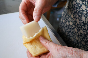 餅巾着を作る高齢女性の手元