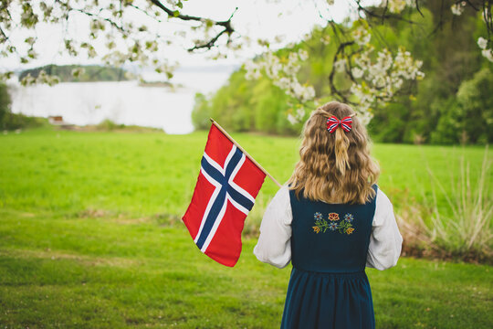 Girl with Norwegian flag looking down at the fjord. 