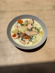 A bowl of salmon soup with vegetables.