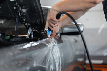 Professional man applies protective ppf film at detailing service. Car care and protection
