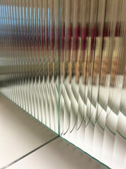 View through the fluted glass corner with mirror, creating repeating mirror image and distorted...