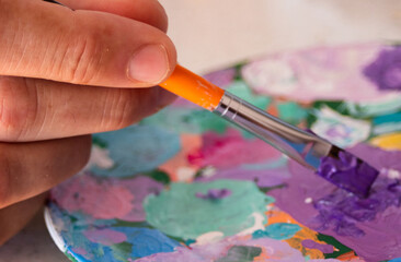 Obraz premium Hand holding a brush and creating colors on his palette.