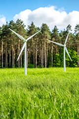 Fototapeta premium Large wind turbines in a lush green field surrounded by trees under a bright blue sky representing sustainable energy environmental progress and clean technology