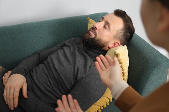 Psychologist working with patient during hypnosis session indoors, closeup