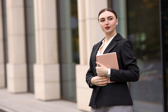 Woman in stylish formal suit with tablet outdoors. Space for text