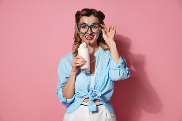 Happy pin-up woman with milk shake on pink background