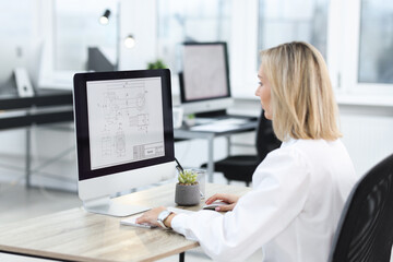 Technician making digital engineering drawing on computer at desk in office