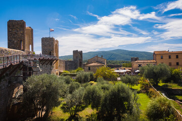 Medieval walls in the small town somewhere in Tuscany during summer day with olives trees and hills on the background forms typical stereotypes of italian countryside when travelling Europe