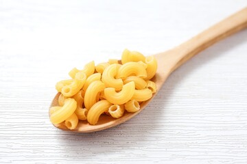 Chifferi rigati pasta in wooden spoon on white background