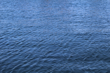 Blue water surface with sun shades. Water background. Sea surface with small waves
