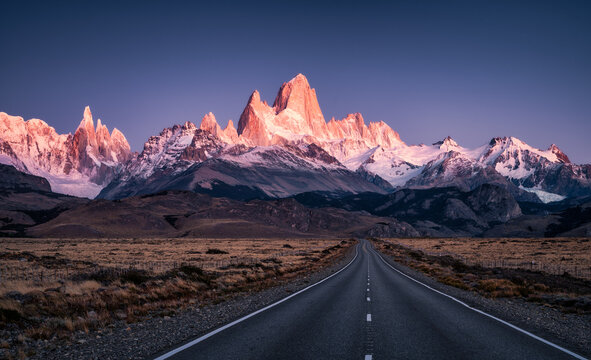 Stunning view of Mount Fitz Roy and Cerro Torre snowcapped steep walls enlightened in red color by morning sun seen from the road to El Chalten, Patagonia, Argentina.