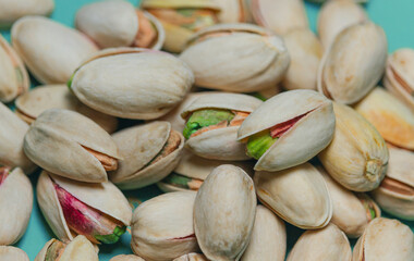 The piled-up nuts are pistachios; the matured nuts are ready to eat. The open-shell nuts have a delicious taste. The pistachio shells are light yellow, with some revealing vibrant green kernels. 