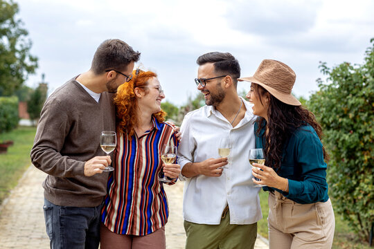 Group of friends with wine glasses on hands at vineyard