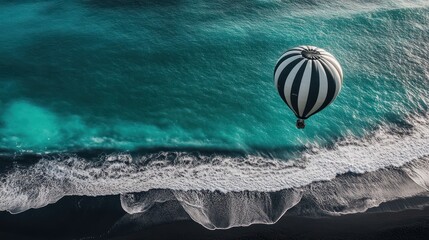 Hot air balloon above ocean waves, black sand beach