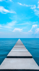 Obraz premium A serene pathway of concrete slabs leads into a tranquil blue sea under a bright sky, evoking feelings of peace and exploration.