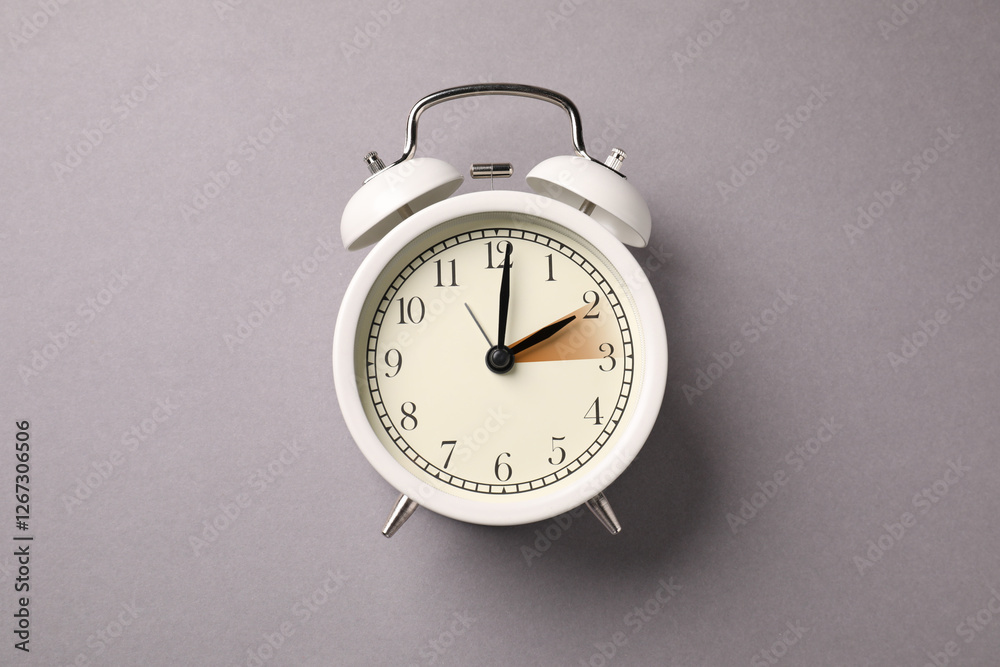 Poster Daylight saving time. White alarm clock on grey background, top view. Highlighted area showing time change by one hour forward