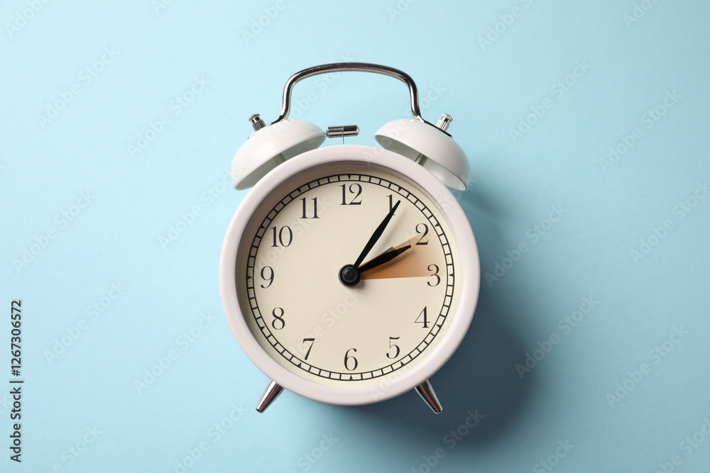 Poster Daylight saving time. White alarm clock on light blue background, top view. Highlighted area showing time change by one hour forward