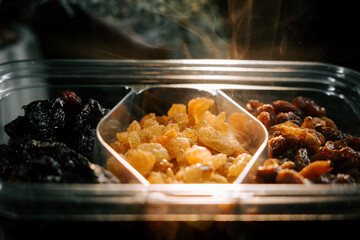 Different types of raisins arranged in a tray with soft light highlighting their textures and colors
