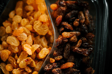 Different varieties of raisins displayed together in a clear container for culinary use and snacking
