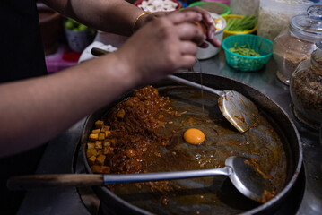 Chef Preparing a Dish by Cracking an Egg into a Pan