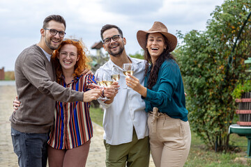 Group of friends with wine glasses on hands at vineyard
