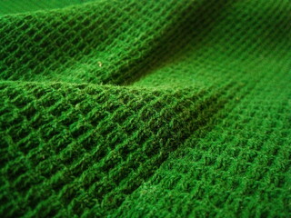Background and texture of green knitted fabric. Background for design. The photo was taken on a mobile phone.