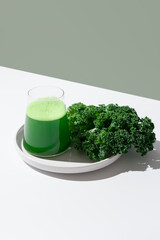 Batido de jugo de col rizada verde y hojas frescas de col rizada sobre fondo verde