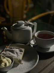 A delectable dessert plate featuring a slice of cheesecake topped with powdered sugar and served with a side of creamy sauce. The warm lighting and cozy atmosphere make the scene even more inviting.