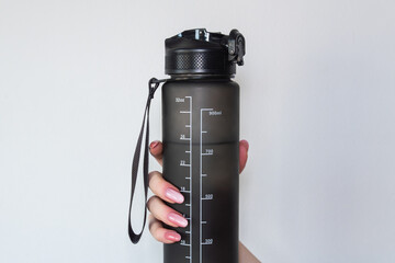 Freshness in Every Sip &ndash; A water bottle in hand. The clean white background emphasizes its simplicity and convenience. A hand holds a sleek, gray water bottle with measurement markings up to 900 mL.