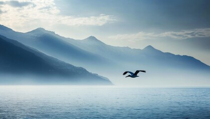 Fototapeta premium Misty lake with mountains and a flying seagull. Scenic landscape. Possible use stock photo