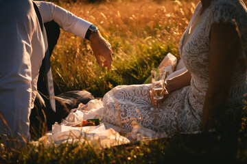 Detail of a picnic at sunset with a bridal dress and champagne