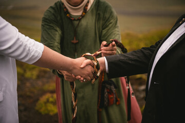 Details of a pagan handfasting ceremony with a weaved ribbon in Iceland