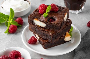 Cheesecake brownies with raspberry on a gray concrete background. Delicious dessert