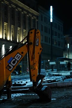 JCB brand excavator at a construction place in the city center at night