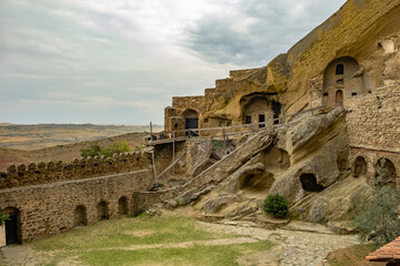 Ancient rock-hewn structures in a historical cave city at dusk amid a scenic landscape