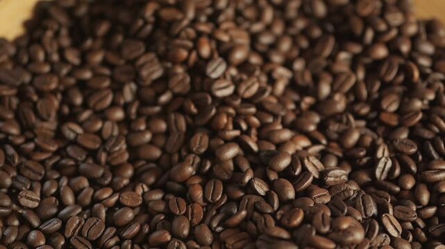 A person is pouring coffee beans into a cup. The coffee beans are scattered all over the table