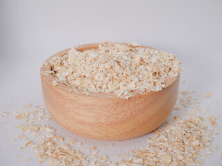 Rustic Wooden Bowl Overflowing with Whole Rolled Oats on White Background