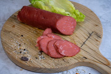 Vegan salami sausage made with washed  flour and bits og vegan cheese fat, sliced on wooden board