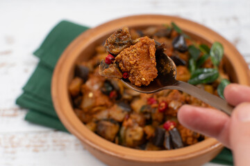 Vegan Indian curry with mock meat, and egg plant,  seitan, plant based  protein. Served in clay dish.