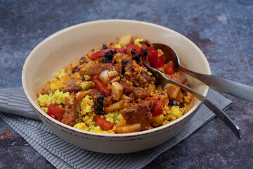 Fried seitan with millet,, cabbage and pepper in light bowl on textured table,