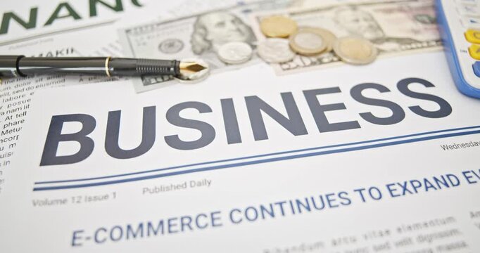 Business and finance concept : A close-up view of a newspaper headline 'BUSINESS' surrounded by financial elements, including currency notes, coins, symbolizing economic growth, e-commerce expansion.