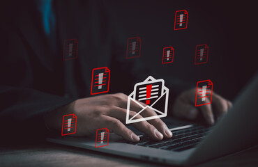 businessman types on laptop with red warning icons email alert symbol, online scams, phishing risks, and cybersecurity threats, emphasizing the need for data protection and security awareness.