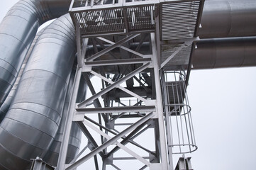 pipeline, iron staircase and balcony close-up against gray sky