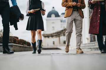 Obraz premium A group of business people walking in an urban city area, showcasing diverse fashion and dynamic movement, creating a lively and modern atmosphere.