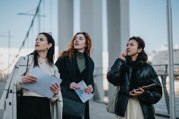 Fototapeta premium Three women are discussing work-related documents and strategizing while outdoors during a meeting. They appear engaged and thoughtful, emphasizing teamwork and collaboration in a professional yet
