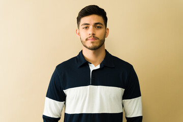 Serious young man posing with blank expression, looking confident
